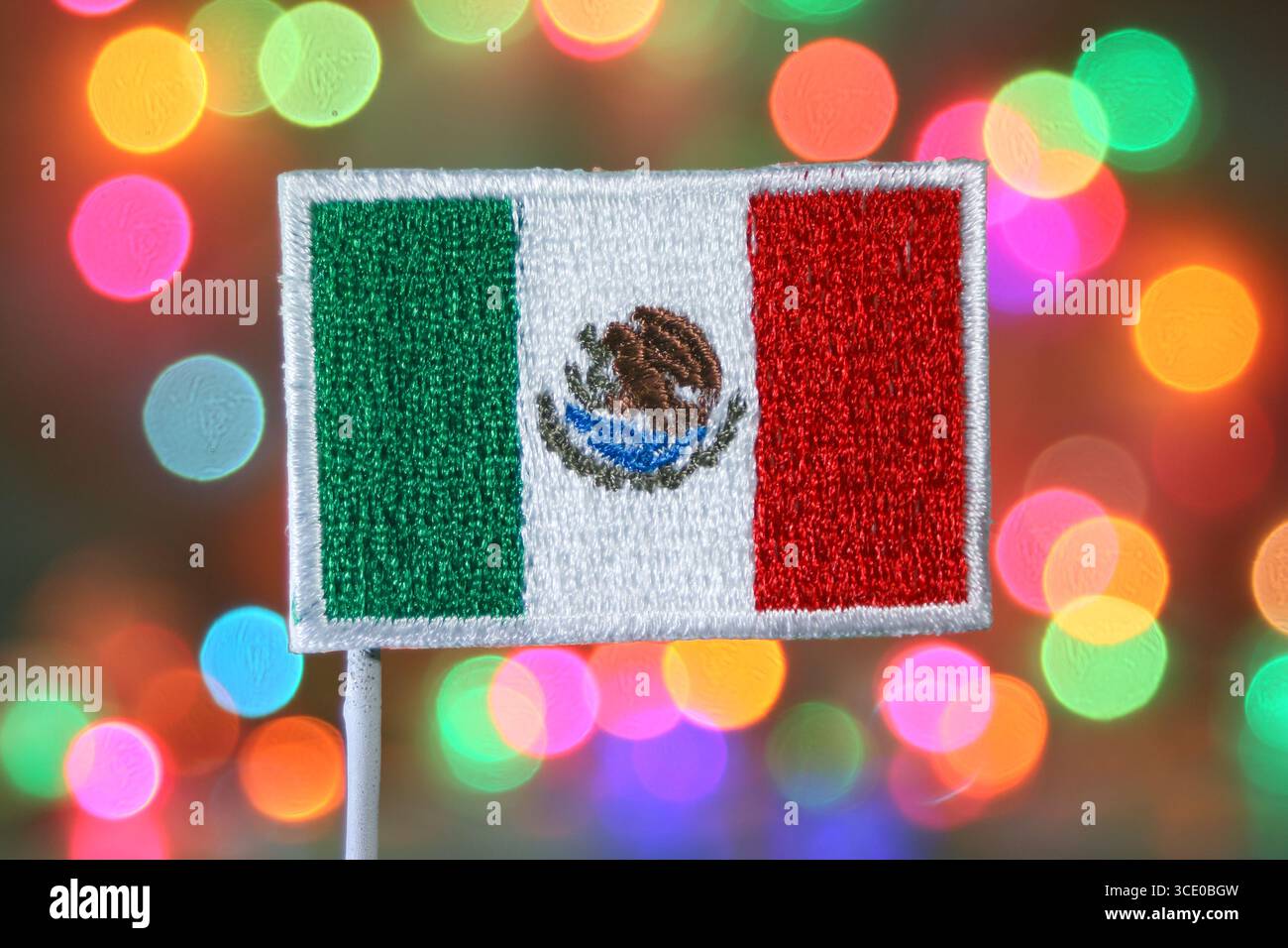 Écusson du drapeau mexicain brodé sur des lumières bokeh arc-en-ciel, atmosphère festive symbolisant la célébration, les fêtes et la fierté culturelle. Banque D'Images