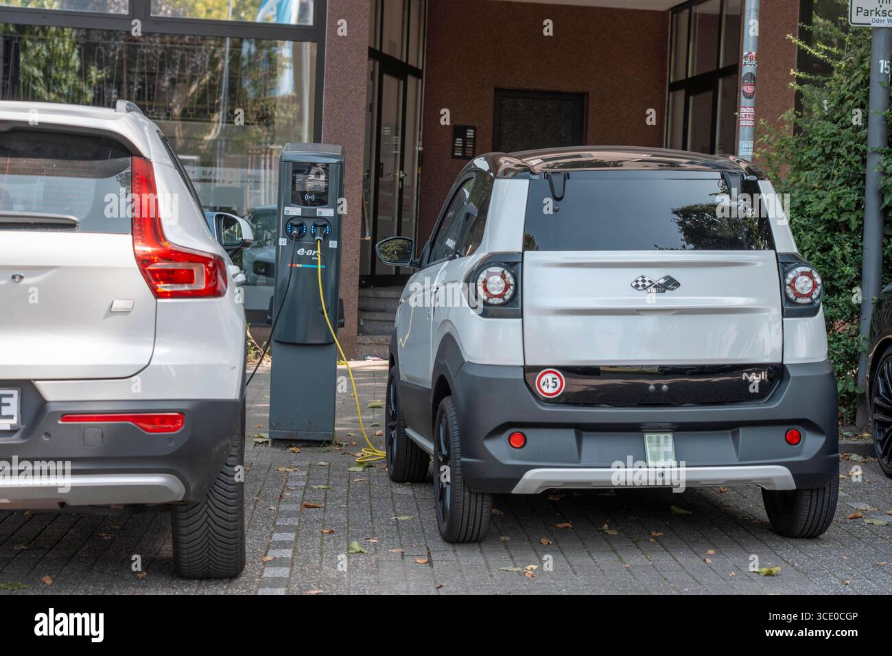 Ligier Myli, Mopedauto, Höchstgeschwindigkeit bis 45 km/h, Leichtwagen, MiniFahrzeug, kann man mit dem Mopedführerschein, Klasse AM, ab 15 Jahren fahren, Elektrofahrzeug, lädt an einer Ladestation, daneben ein normales E-auto, beim Ladevorgang, Mopedauto *** Ligier Myli, voiture cyclomotrice, vitesse maximale jusqu'à 45 km h, véhicule léger, mini Banque D'Images