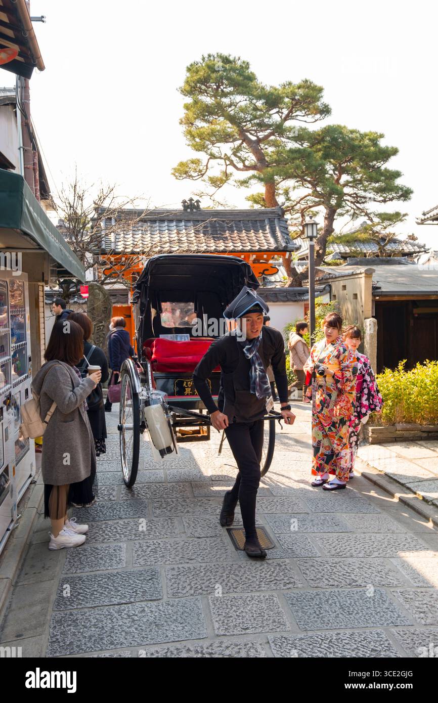 Jeune homme japonais tire un pousse-pousse vide vers le bas, étroit, Kinencho, Higashiyama-ku, Kyoto, Japan Banque D'Images