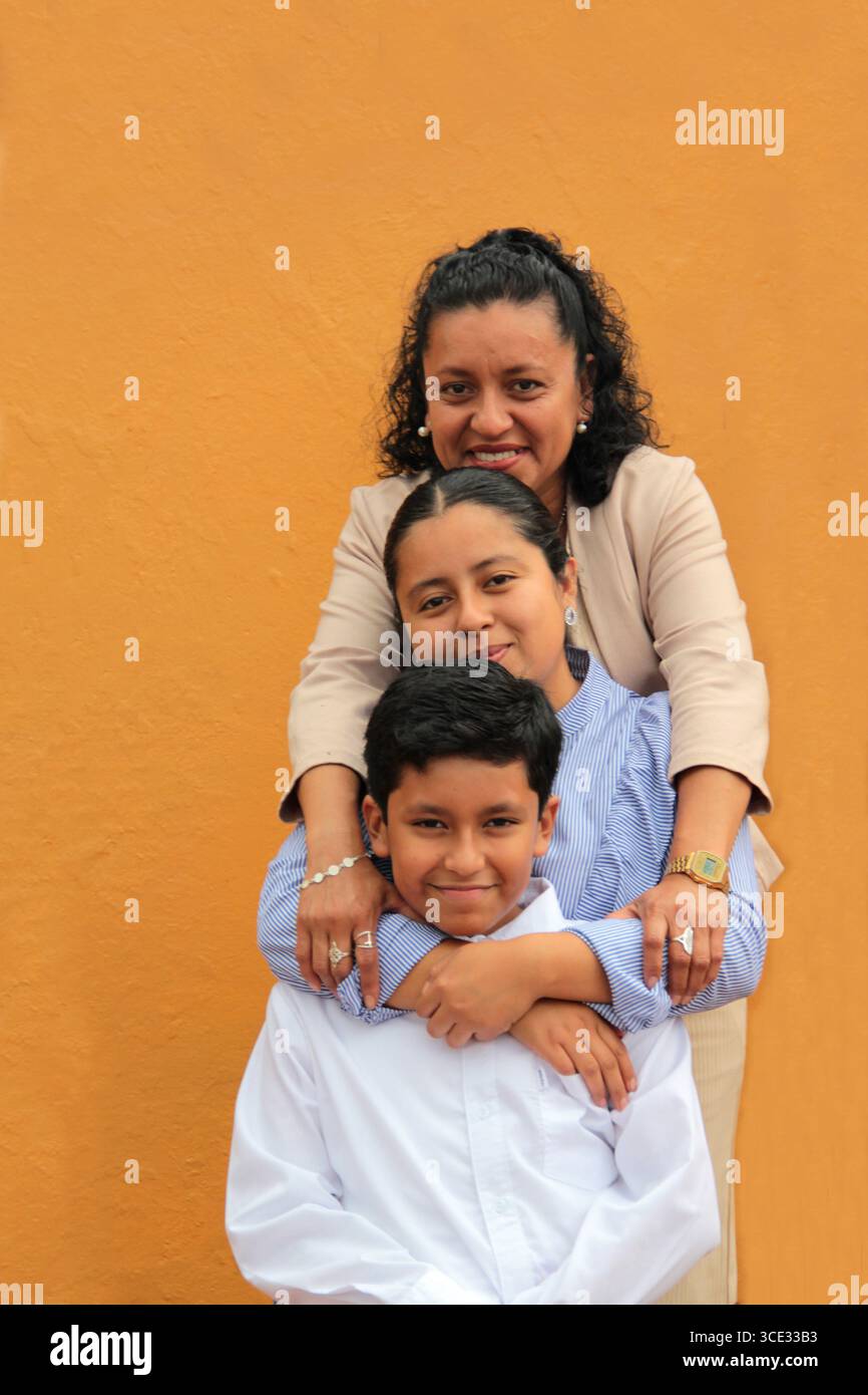 La mère, la fille et le fils latino-américains à la peau foncée montrent leur amour avec des câlins et célèbrent la fête des mères avec leur famille Banque D'Images La mère, la fille et le fils latino-américains à la peau foncée montrent leur amour avec des câlins et célèbrent la fête des mères avec leur famille Banque D'Images