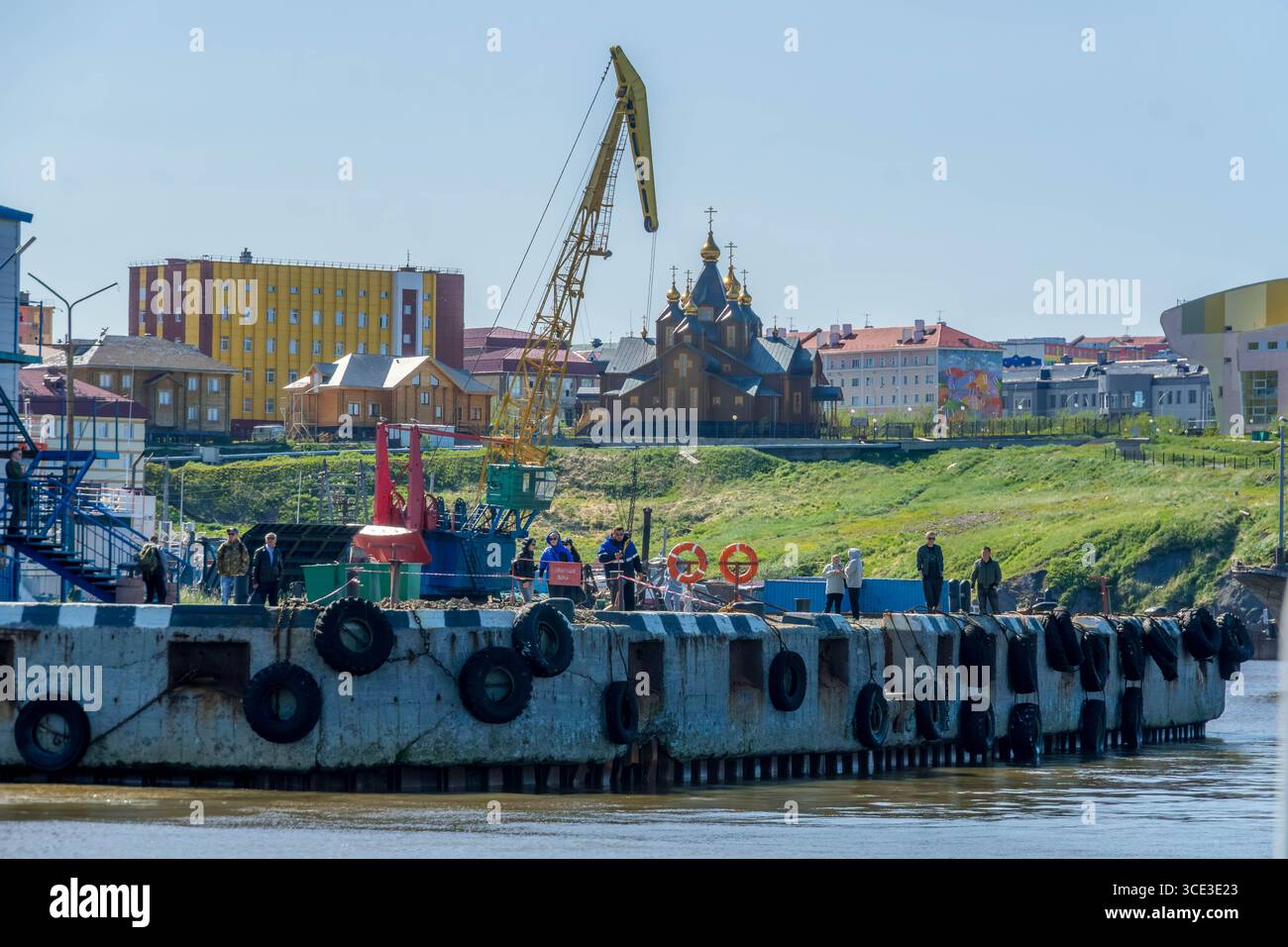 Habitants sur un quai en béton avec grue jaune sur la côte de la mer de Béring à Anadyr, Russie. Banque D'Images