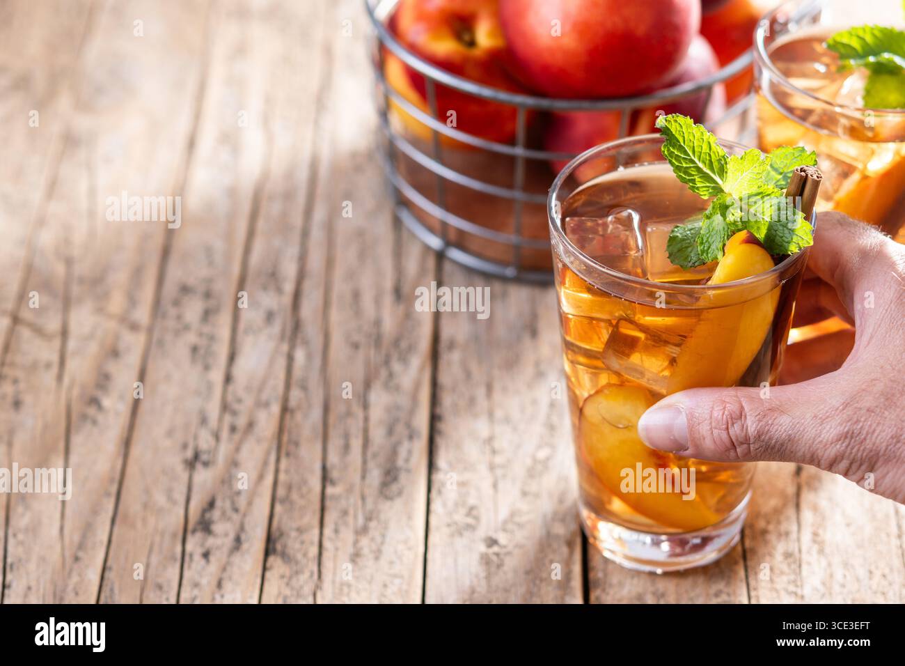 Rafraîchissant thé glacé à la pêche dans un verre avec des glaçons sur une table en bois Banque D'Images