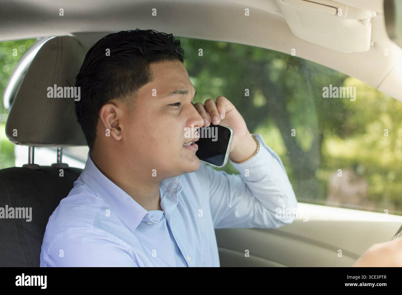 Un conducteur masculin fait un appel en conduisant. Jeune conducteur utilisant le téléphone pendant la conduite Banque D'Images