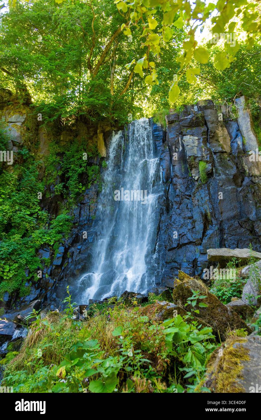 La cascade Vaucoux tombe gracieusement sur des rochers sombres, entourée d'une végétation luxuriante dans la région du Puy de Dôme. Auvergne Rhône Alpes. France Banque D'Images