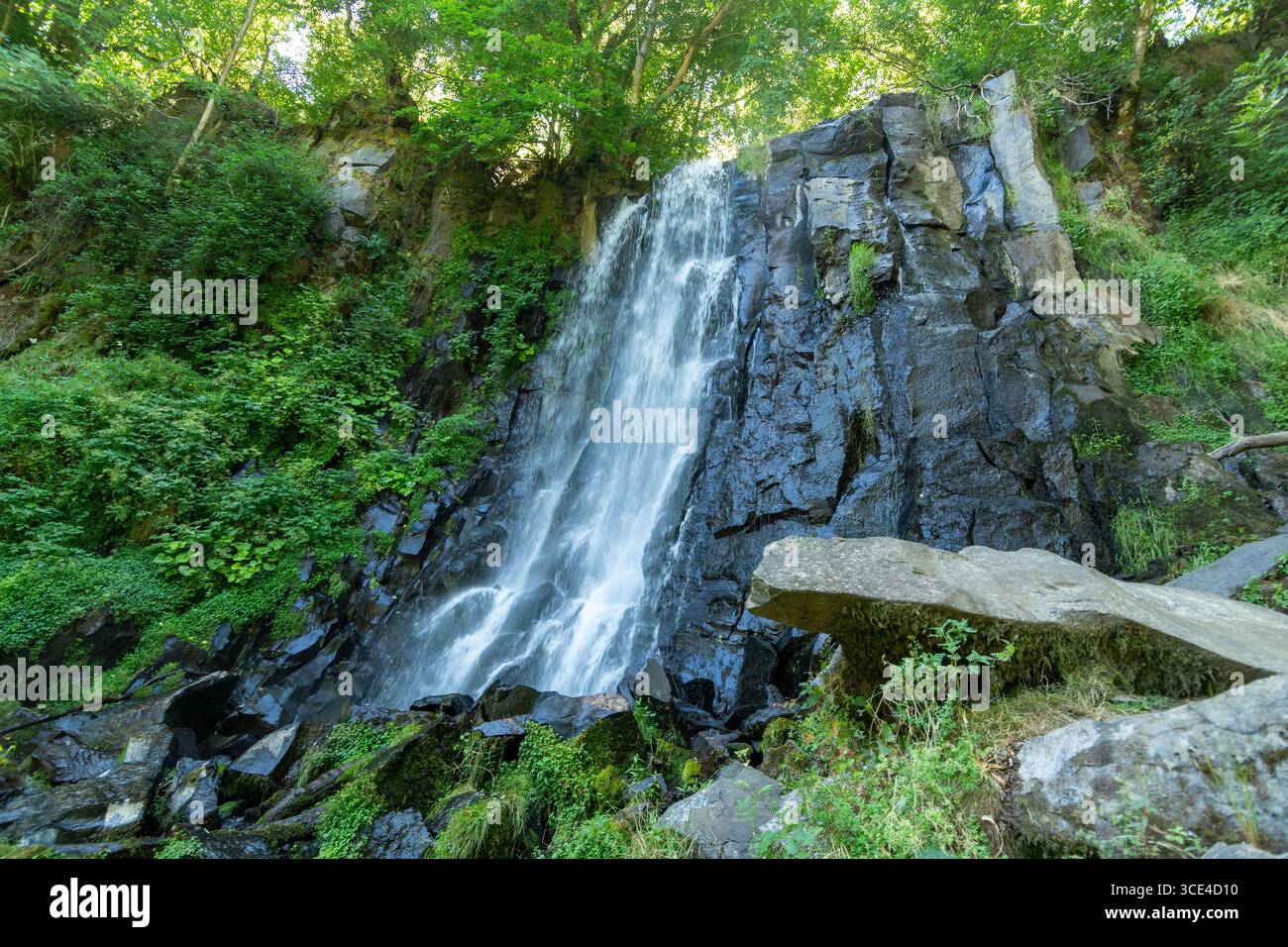 La cascade Vaucoux tombe gracieusement sur des rochers sombres, entourée d'une végétation luxuriante dans la région du Puy de Dôme. Auvergne Rhône Alpes. France Banque D'Images