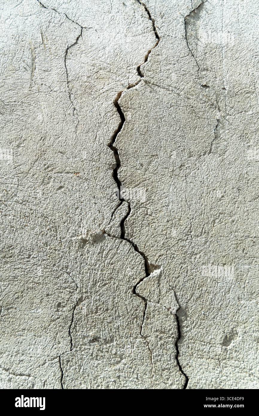 Une fissure perceptible traverse un mur de béton, soulignant la texture de la surface. Le mur montre des signes d'usure et de vieillissement typique Banque D'Images
