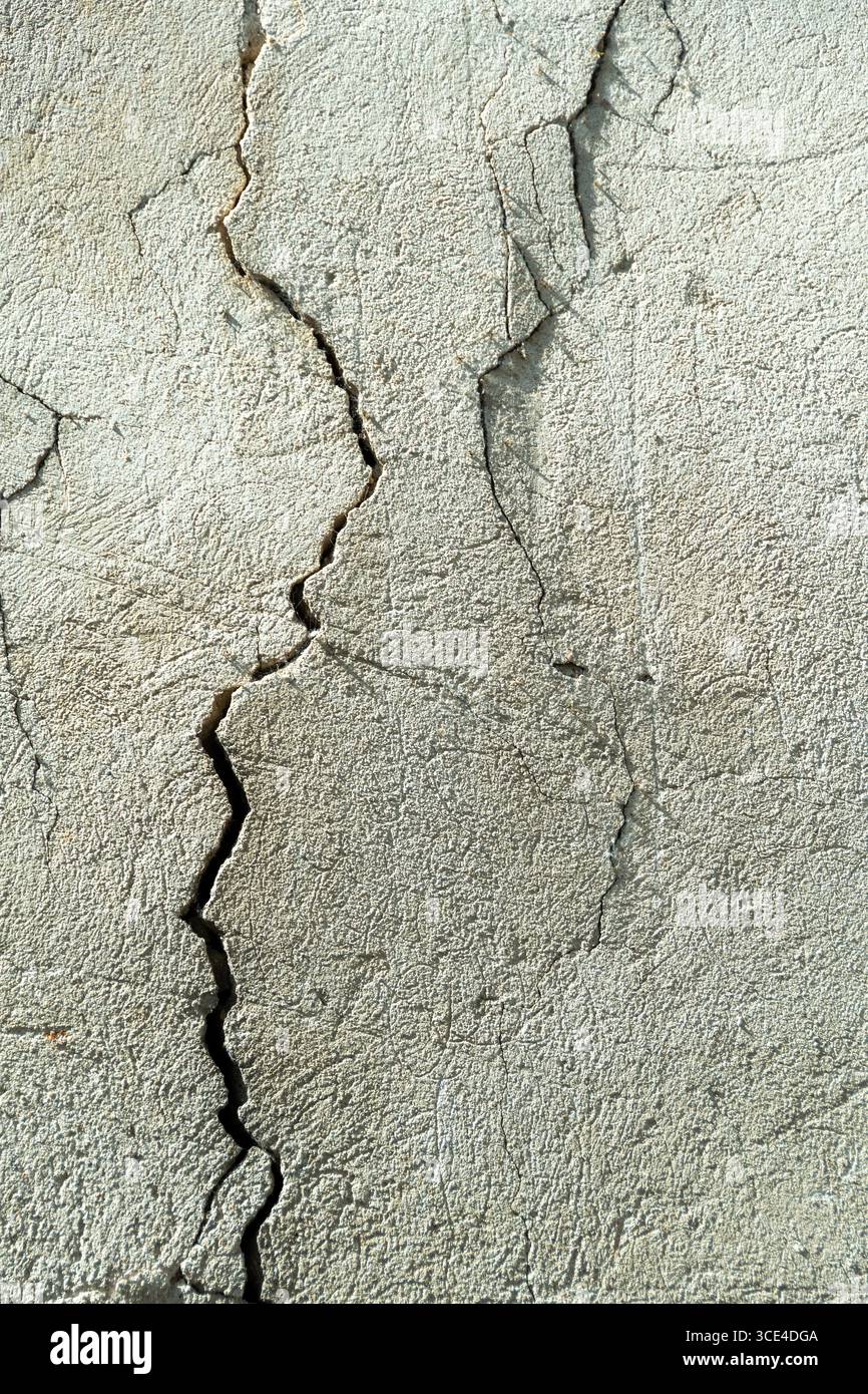 Une fissure perceptible traverse un mur de béton, soulignant la texture de la surface. Le mur montre des signes d'usure et de vieillissement typique Banque D'Images