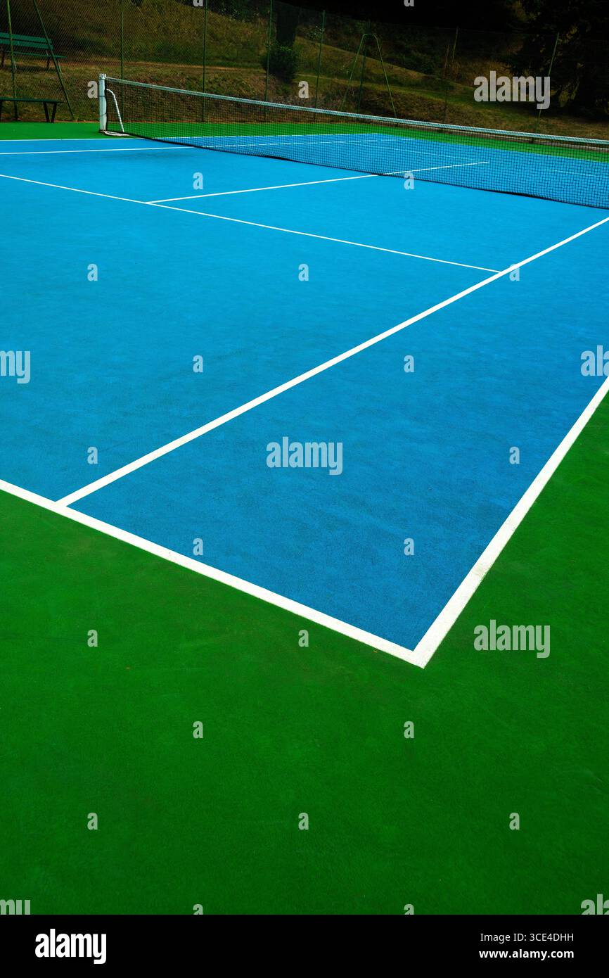 Un court de tennis vibrant avec une surface bleue contraste avec les bords verts. Les lignes blanches brillantes créent des limites claires. France Banque D'Images