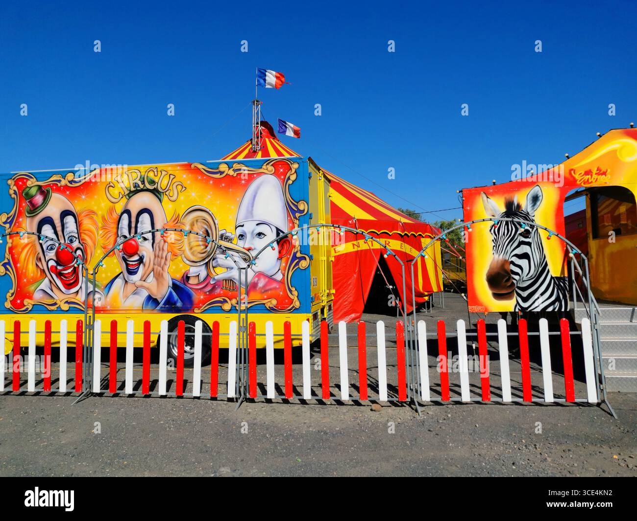Tente de cirque vibrante ornée de couleurs vives et d'images de clown, aux côtés de véhicules distinctifs. France - Image de stock capturée avec un smartphone