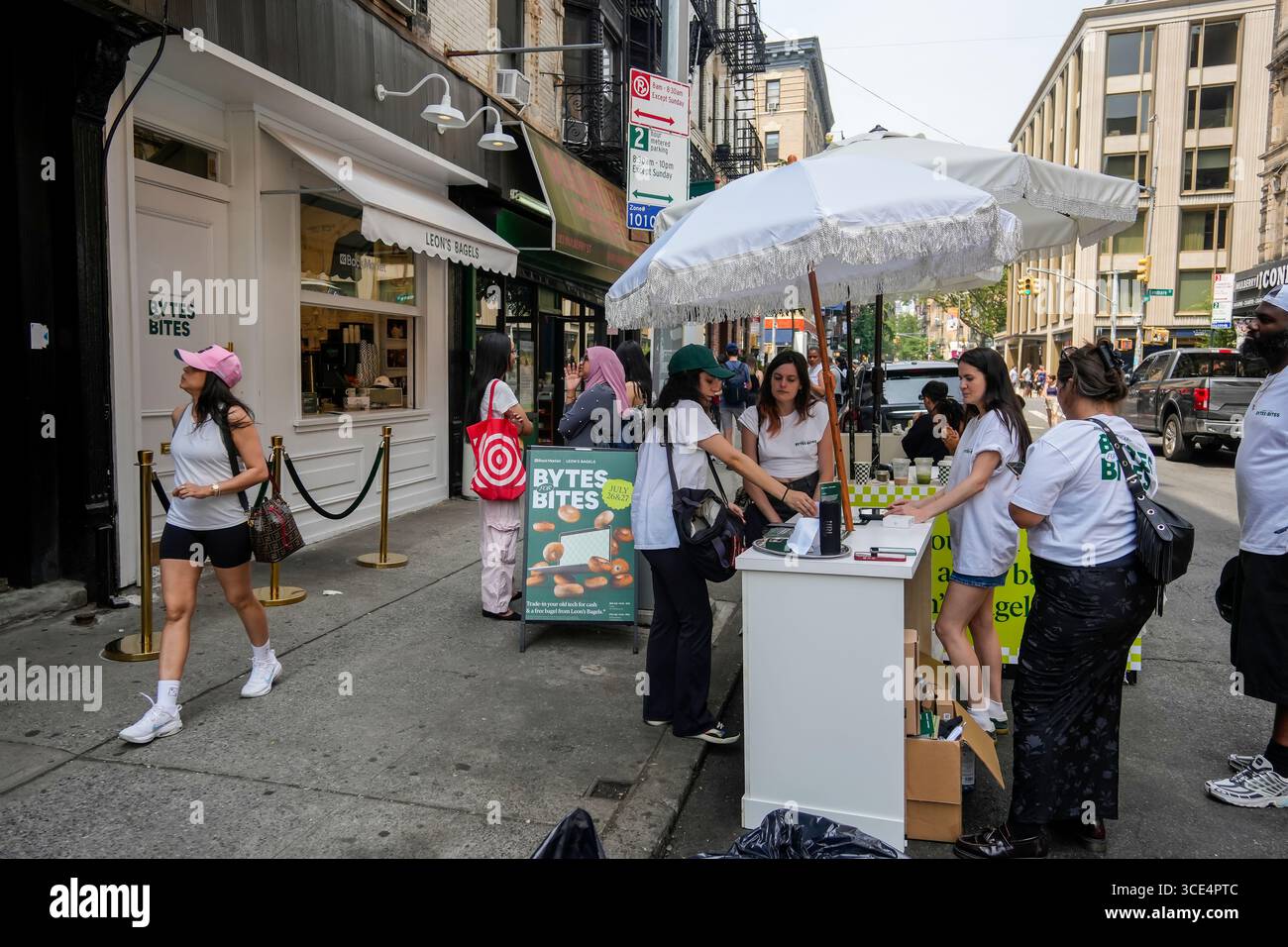 Ambassadeurs de la marque devant Leon’s Bagels dans le quartier Lower East Side de New York pour la promotion « Bites for Bytes » de Backmarket le samedi 26 juillet 2024. Backmarket, un revendeur de technologies d'occasion, achète des smartphones d'occasion admissibles en donnant de l'argent et un bagel gratuit. (© Richard B. Levine) Banque D'Images