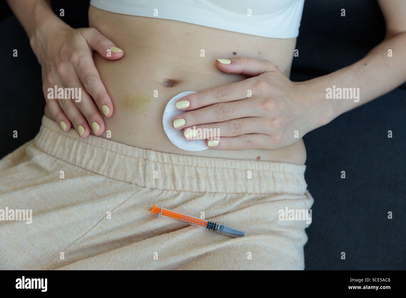 L'image représente une personne qui se prépare à administrer une injection, mettant en évidence une approche axée sur la santé avec un coton et une seringue situés à proximité Banque D'Images