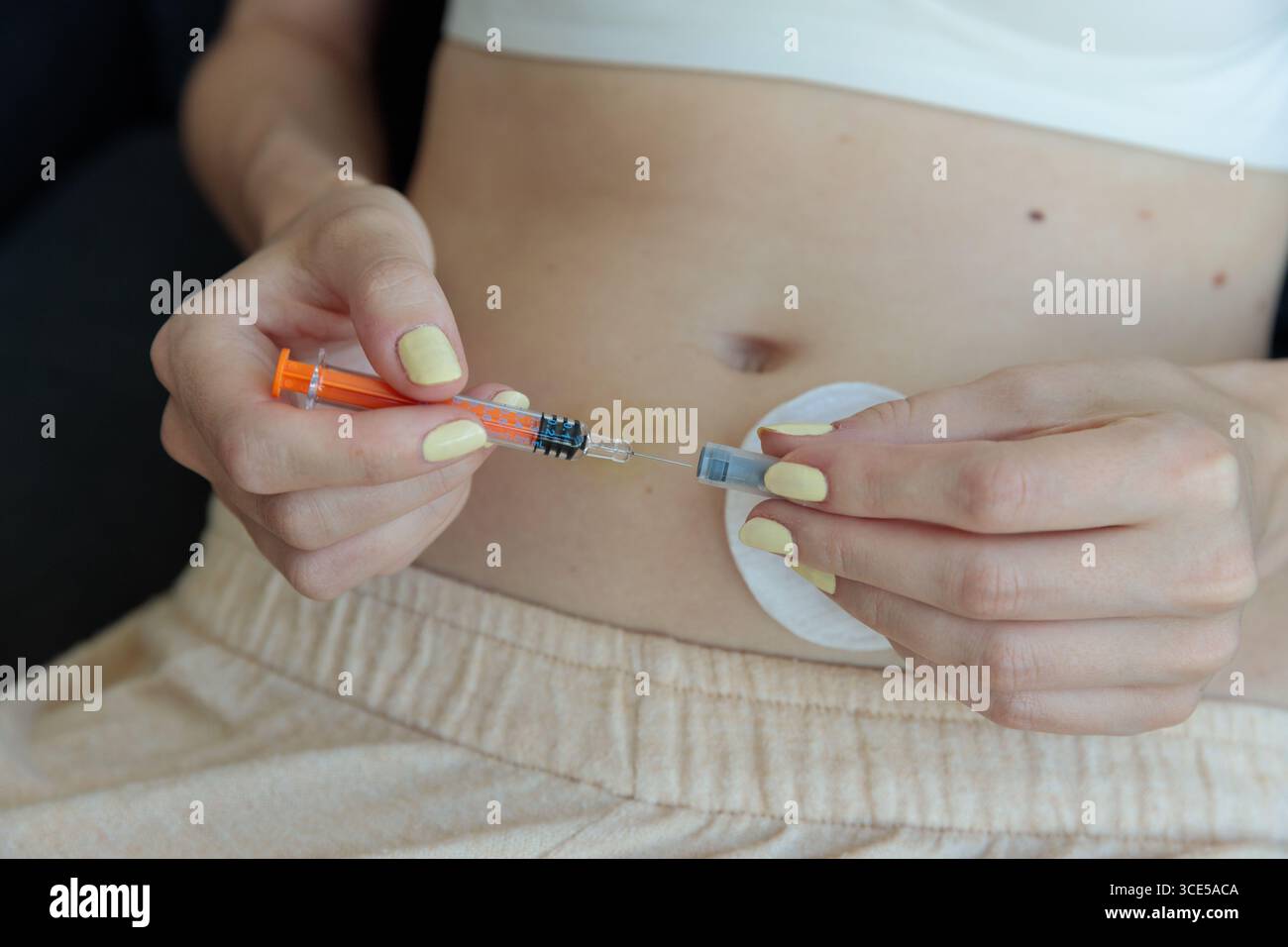 L'image capture les mains d'une personne prête à administrer une injection dans l'abdomen, mettant en évidence une seringue et un coton, mettant l'accent sur les thèmes de h. Banque D'Images