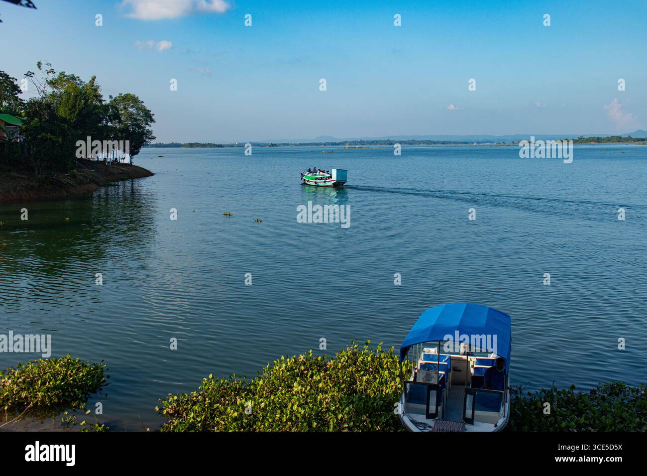 Bateau bangladais coloré ancré sur le rivage serein du lac Kaptai avec vue panoramique sur l'île Banque D'Images