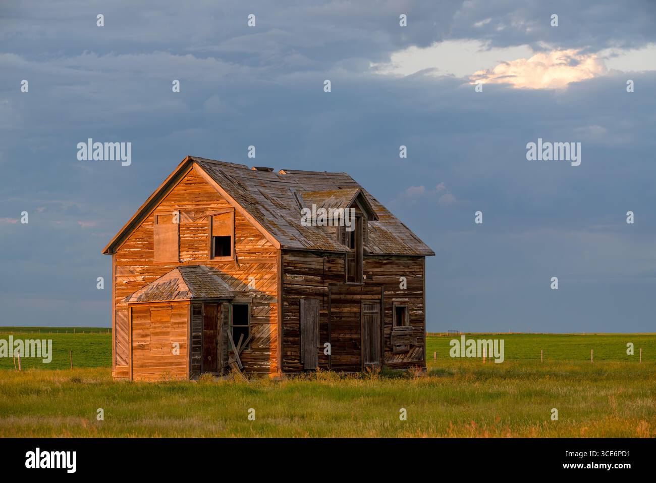 De sombres nuages orageux survolent une vieille maison abandonnée dans les Prairies au nord de Rush Lake, en Saskatchewan Banque D'Images