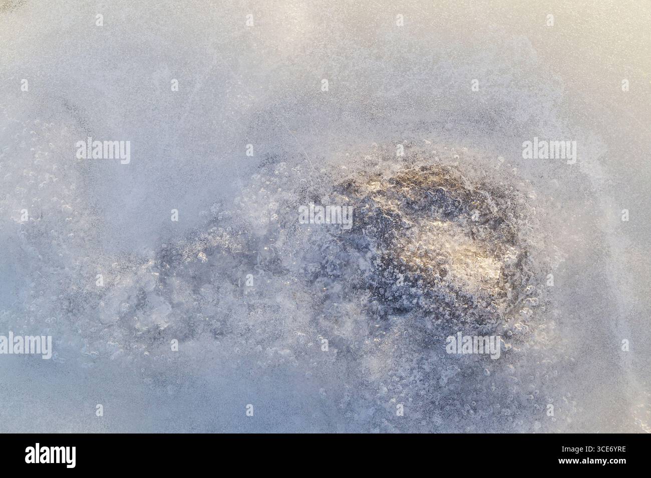 Gros plan de bulles et d'une pierre sous glace sur un lac gelé en hiver, vu d'en haut. Fond texturé plein cadre abstrait. Copier l'espace. Banque D'Images