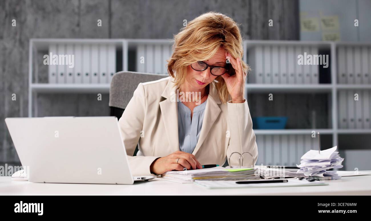 Femme d'affaires épuisée : submergée par les chiffres, frustrée par la planification budgétaire Banque D'Images