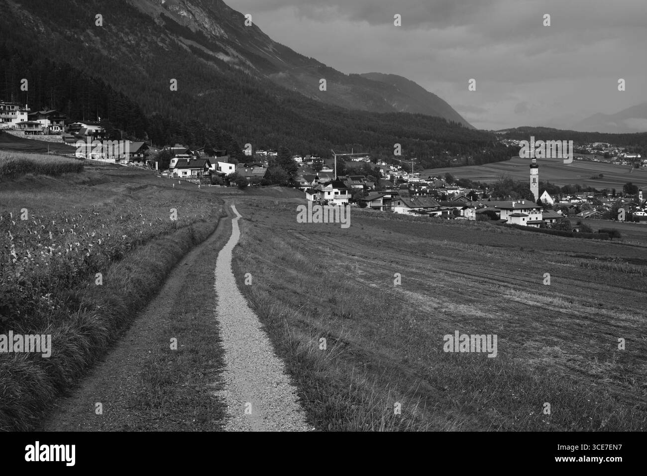 Schwarz-Weiß-Aufnahme von Thaur mit Berglandschaft und Feldweg Banque D'Images