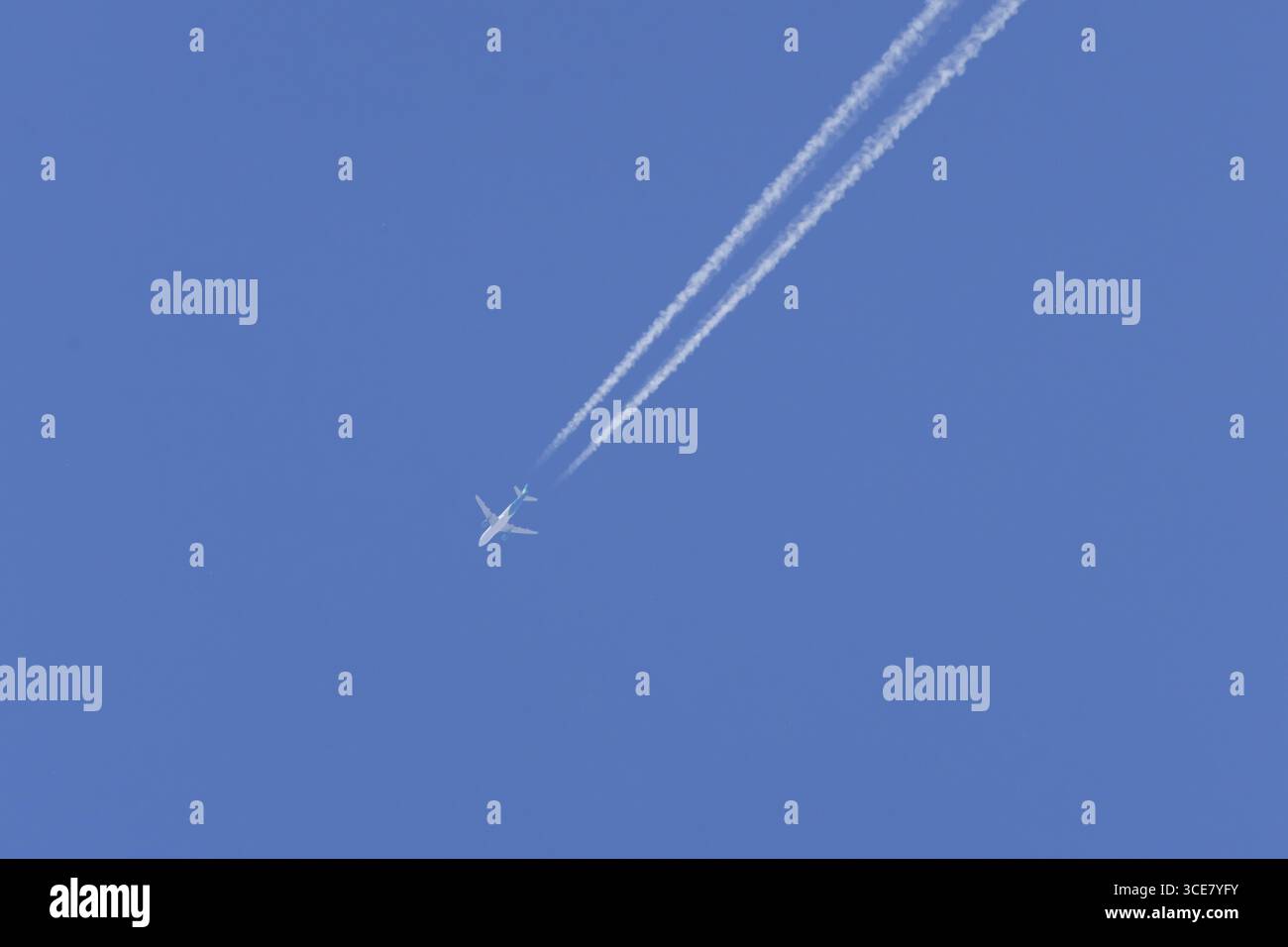 Avion de passagers à réaction en vol dans un ciel bleu avec des traînées de vapeur ou des traînées derrière, Angleterre, Royaume-Uni Banque D'Images