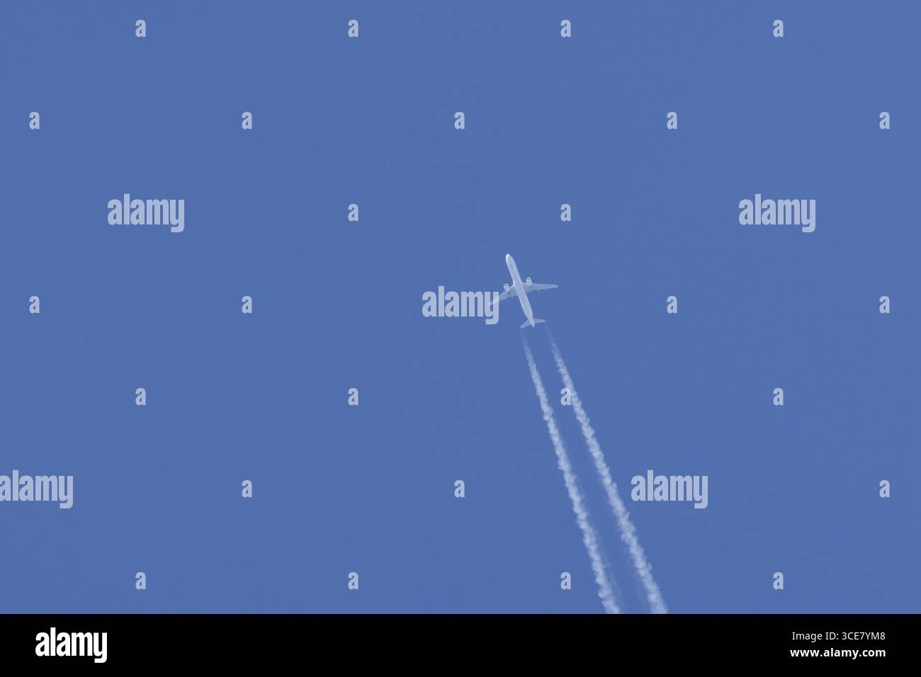 Avion de passagers à réaction en vol dans un ciel bleu avec des traînées de vapeur ou des traînées derrière, Angleterre, Royaume-Uni Banque D'Images