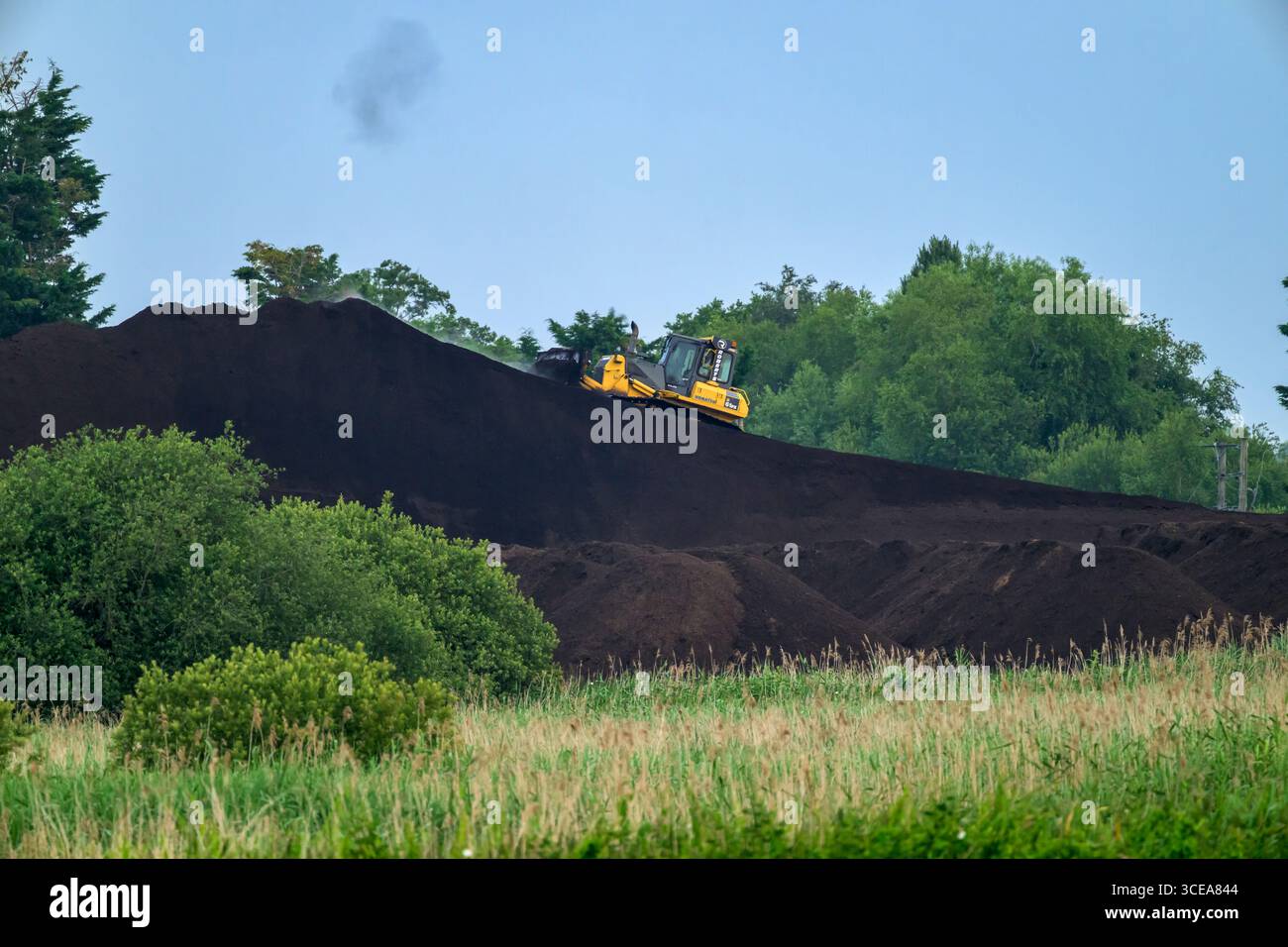 Extraction de tourbe et gestion de la tourbe à Meare dans le Somerset, avec tracteur sur une petite colline de tourbe qui a été accumulé dans le cadre de la gestion de la tourbe Banque D'Images