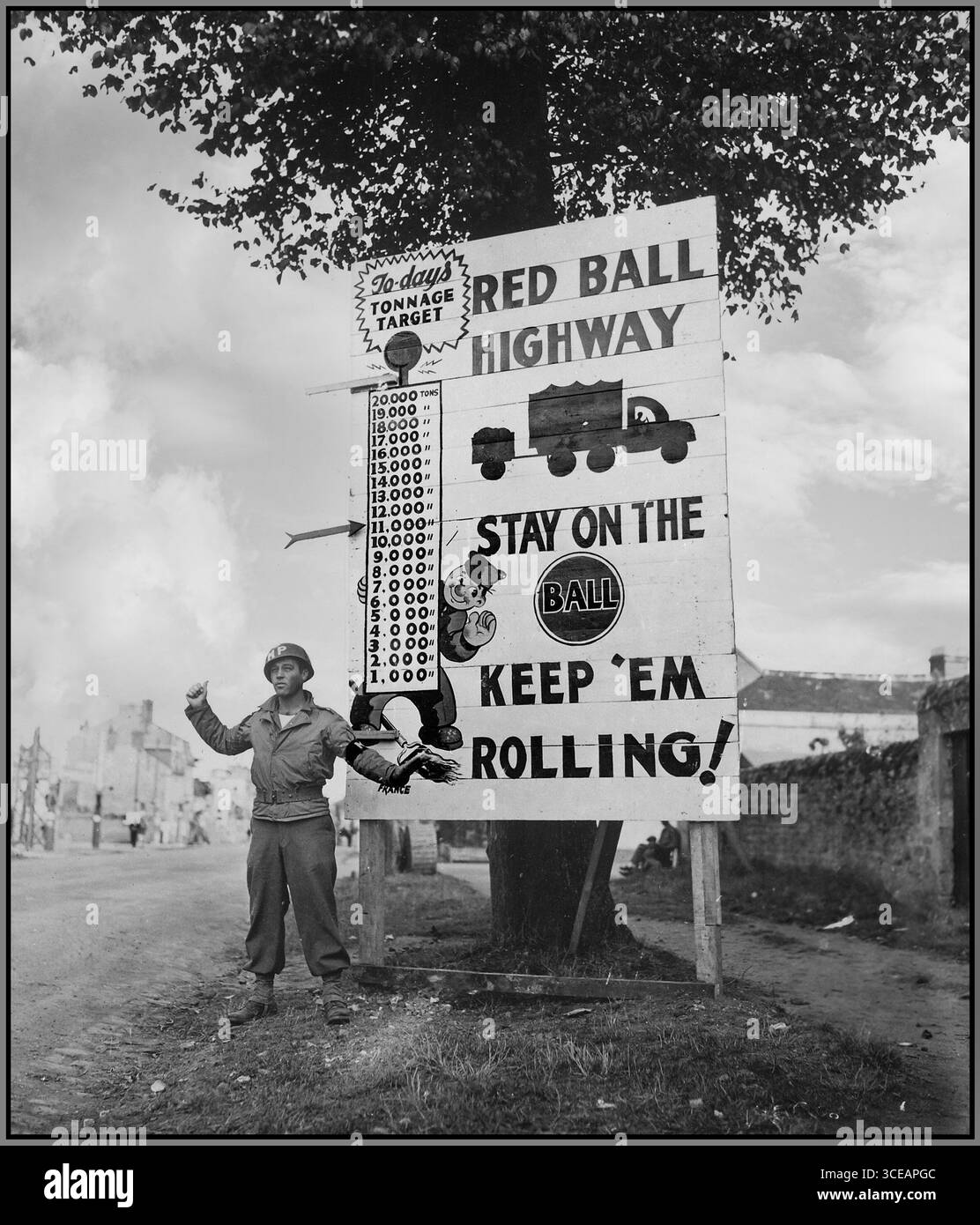 Routes du convoi militaire français de l'invasion du jour J 1944 le caporal Charles H. Johnson du 783e bataillon de la police militaire, fait des vagues sur un convoi motorisé « Red Ball Express » précipitant du matériel prioritaire vers les zones avancées, près d'Alençon, France WW2 le Red Ball Express était une opération d'approvisionnement massive établie après l'invasion du jour J pour acheminer du matériel prioritaire, du carburant et des munitions vers les zones avancées alliées. L'opération est devenue un symbole de l'innovation logistique et du rôle essentiel des soldats américains dans le soutien de l'avancée alliée à travers la France. Banque D'Images