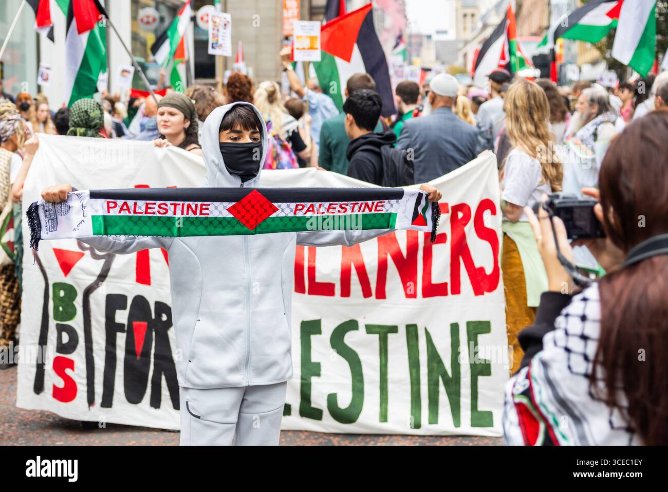 Leeds, Royaume-Uni. 16 AOÛT 2025. La personne tient le foulard de la Palestine alors qu'environ 600 personnes ont assisté à la 'marche du Nord pour la Palestine' dans le centre de Leeds. Avec une petite contre-manifestation pro-israélienne au point de départ sur la place Saint-Pierre, la marche principale a emprunté un itinéraire sinueux à travers le centre-ville, allumant des fusées éclairantes et arrêtant brièvement la circulation à l'extérieur de plusieurs endroits. Une arrestation a été faite pour un signe interdit. Crédit Milo Chandler/Alamy Live News Banque D'Images