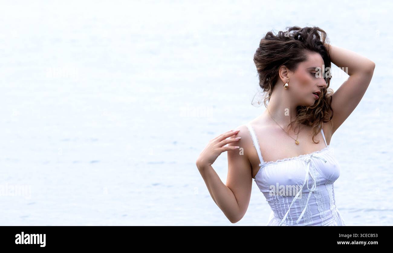 Tayport à Fife, en Écosse. Femme à la mode portant une robe blanche courte se tient dans la rivière Tay lors d'une séance photo sur le thème de la fantaisie l'après-midi, Royaume-Uni Banque D'Images