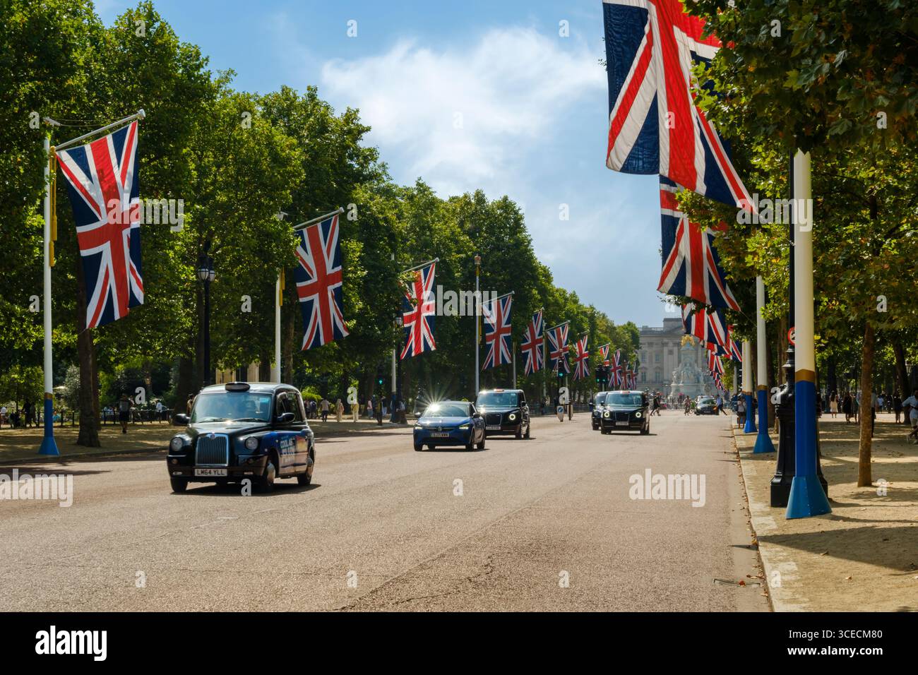 Londres, Angleterre - Londres taxis passez devant les nombreux Union Jacks qui bordent le Mall en regardant vers Buckingham Palace dans le centre de Londres. Banque D'Images