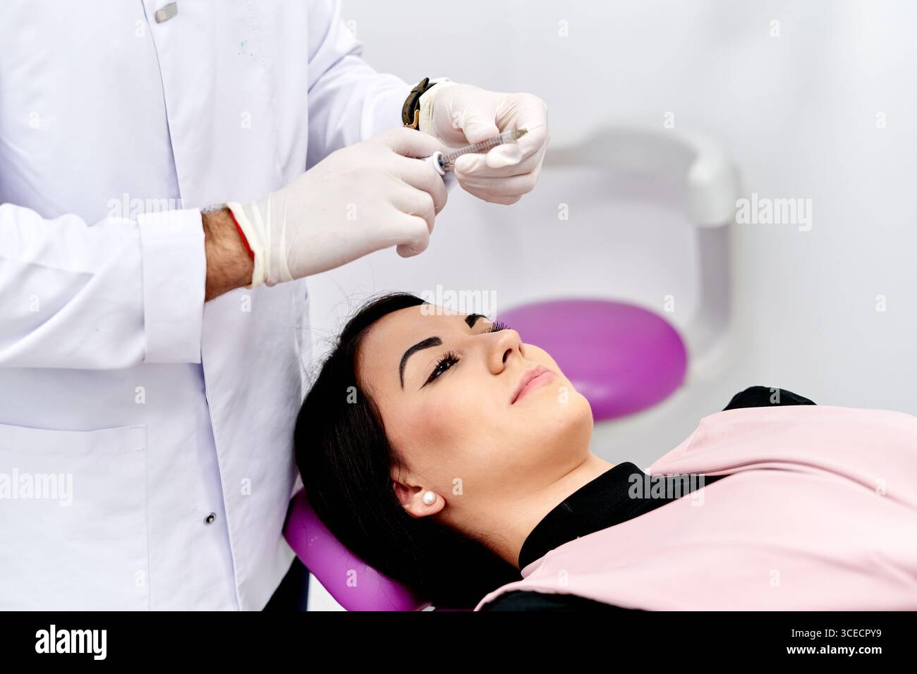 Un patient reçoit un traitement cosmétique du visage dans une clinique médicale. Le médecin se prépare pour la procédure, assurant une application sûre et efficace f Banque D'Images