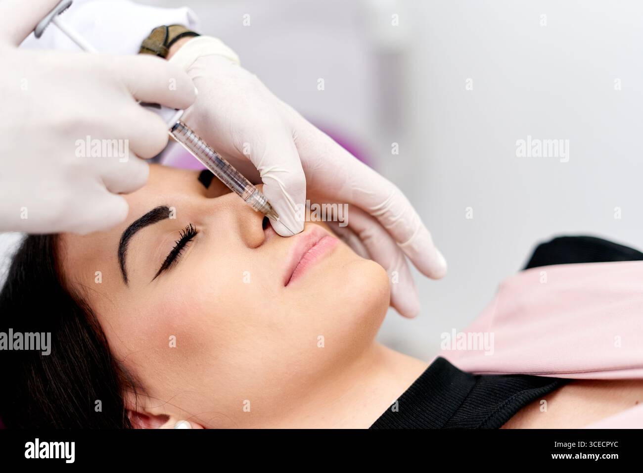 Patient recevant une injection cosmétique administrée par un professionnel dans un cadre clinique. La procédure vise à améliorer les traits du visage et la promo Banque D'Images