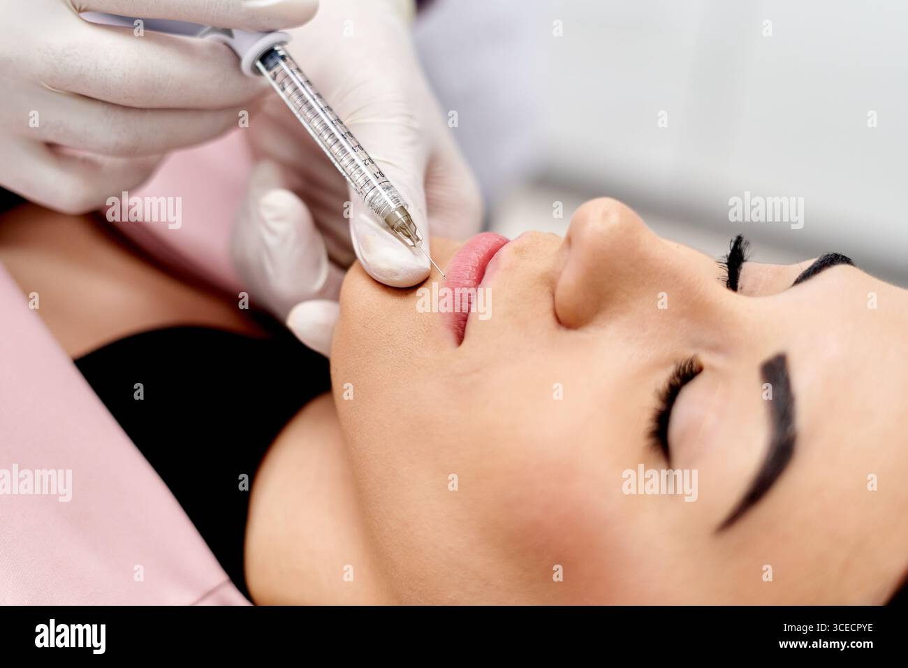 Un professionnel de la santé administre une injection d'acide hyaluronique à une femme dans un cadre clinique, en se concentrant sur l'amélioration des traits faciaux et la promotion d'un Banque D'Images