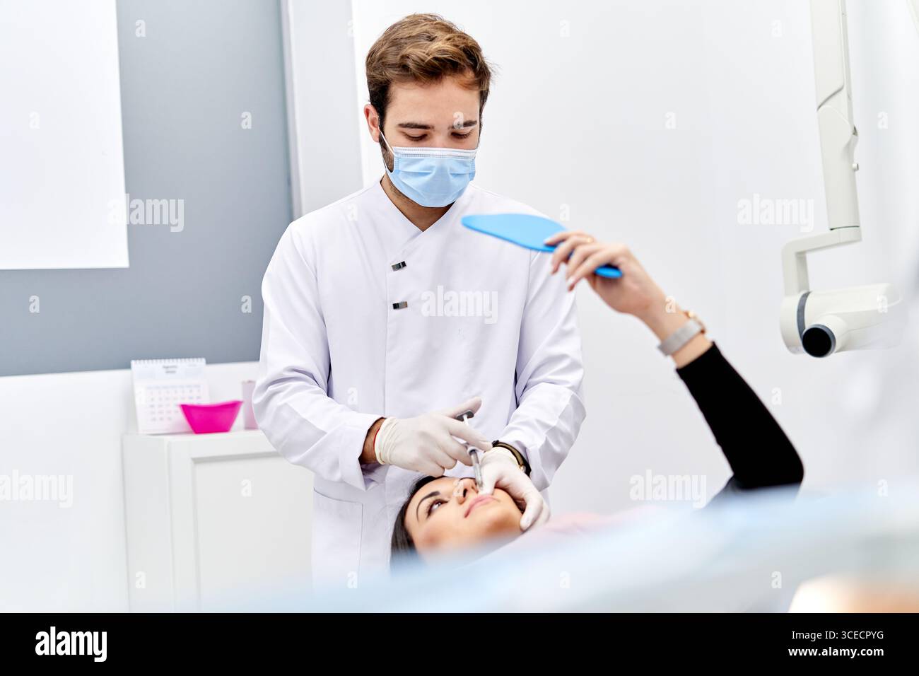 Un médecin, portant des gants stériles blancs, administre soigneusement une injection d'acide hyaluronique à un patient dans un cabinet médical moderne, en mettant l'accent sur le Precisi Banque D'Images