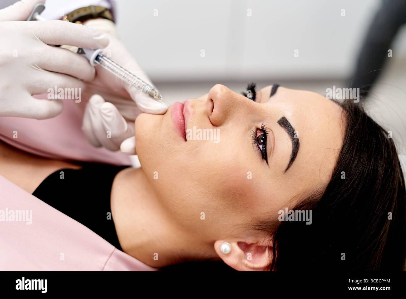Vue rapprochée d'une procédure cosmétique lorsqu'un spécialiste administre une injection de rehaussement des lèvres à l'aide d'une seringue. Le patient est couché confortablement, showc Banque D'Images