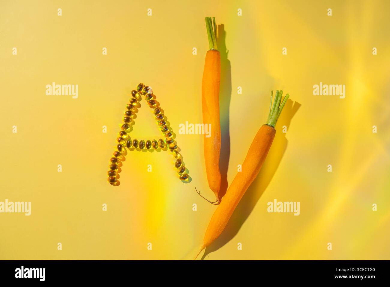 Capsules Softgel formant la lettre A à côté de deux carottes fraîches sur un fond jaune vif. Cette image met en évidence le concept de vitamine A en tant que hea Banque D'Images