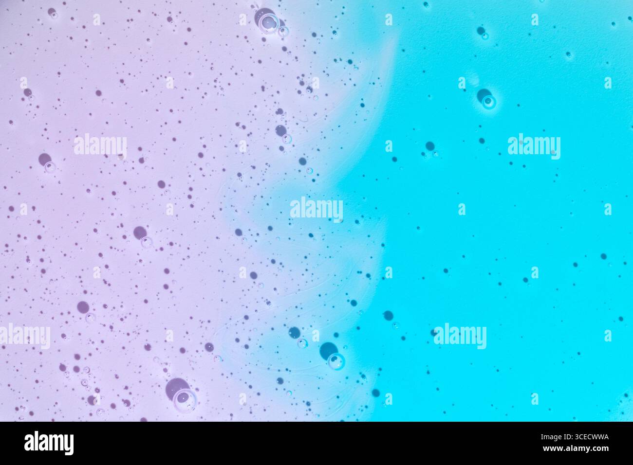 Vue aérienne gros plan de gouttelettes de gel cosmétique éclatantes en violet et bleu, créant une texture dynamique sur un fond dégradé. Parfait pour beau Banque D'Images