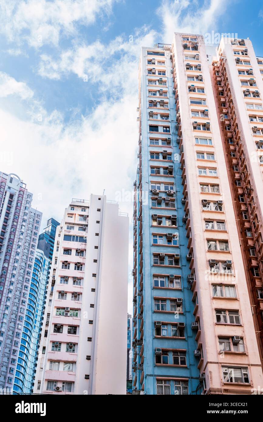 Les grands bâtiments résidentiels dominent le paysage urbain de Hong Kong, mettant en valeur l'architecture vibrante et la densité urbaine sur fond de ciel bleu clair et Banque D'Images