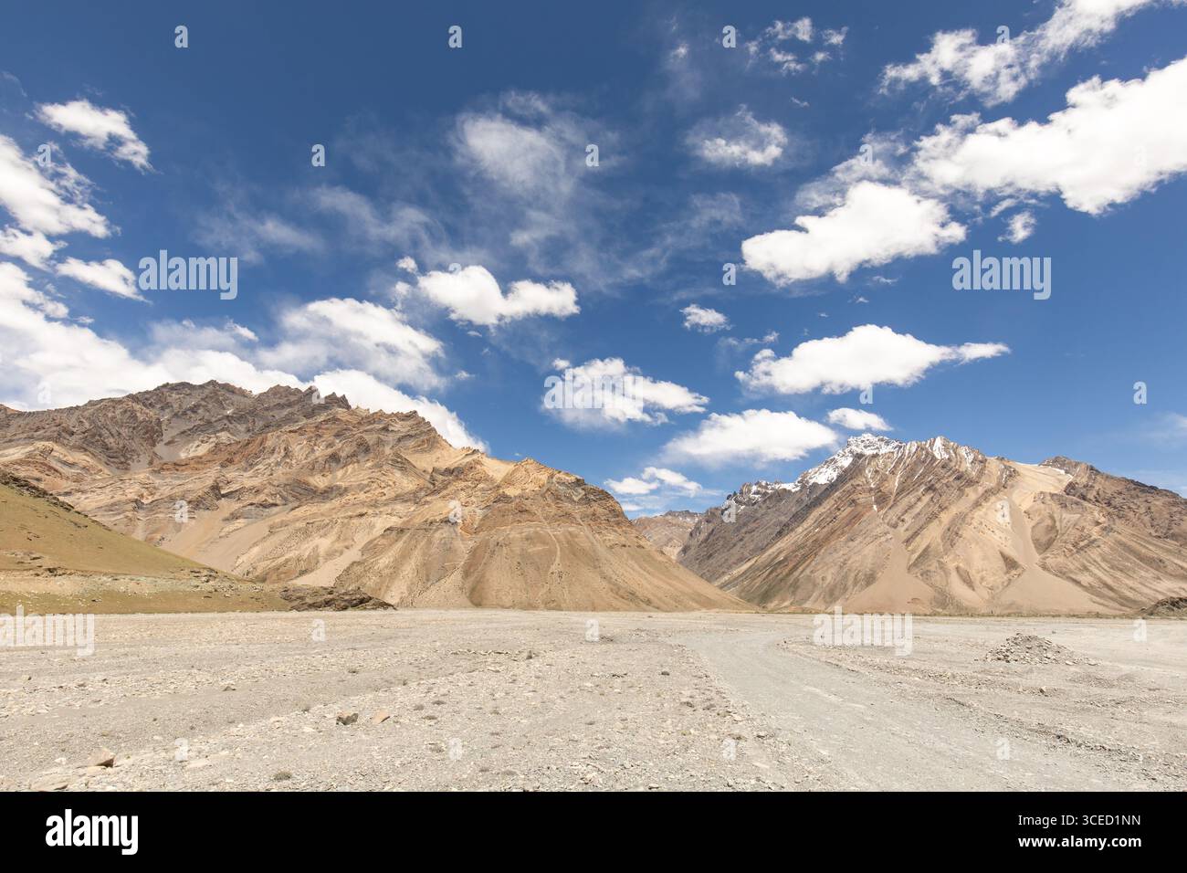 Des montagnes majestueuses s'élèvent sous un ciel bleu clair, capturées dans la magnifique vallée du Zanskar au Ladakh, en Inde. Le terrain sec et rocheux contraste magnifiquement Banque D'Images