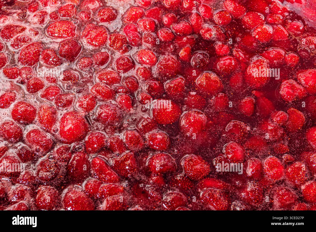 Une image en gros plan de la vibrante confiture de fraises maison, mettant en valeur la texture riche et la couleur des fraises fraîches et du sucre, parfait pour le petit déjeuner spre Banque D'Images