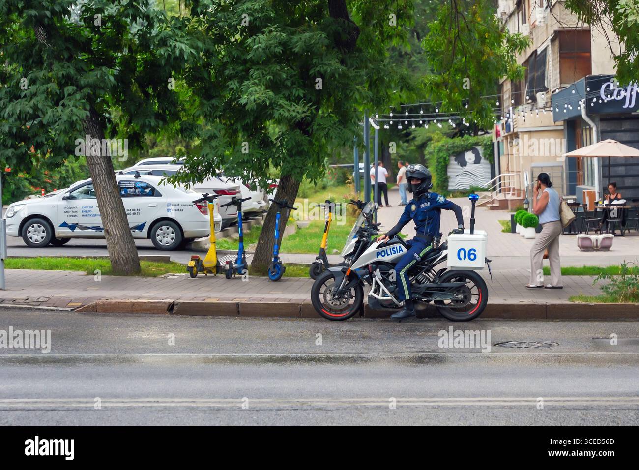 Almaty, Kazakhstan - 14 juillet 2025 : un policier à moto se tient au bord de la route. Sécurité publique Banque D'Images