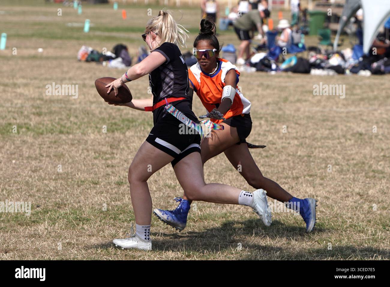 Joueuse de football de drapeau féminin courant avec le ballon @ Flagapalooza 2025 Flag Football Tournament, Newlands Park, Cheltenham, Royaume-Uni, Banque D'Images