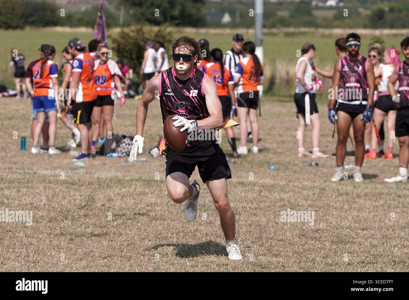 Joueur masculin de football drapeau courant avec le ballon au Flagapalooza 2025 Flag Football Tournament, Newlands Park, Cheltenham, Royaume-Uni, Banque D'Images