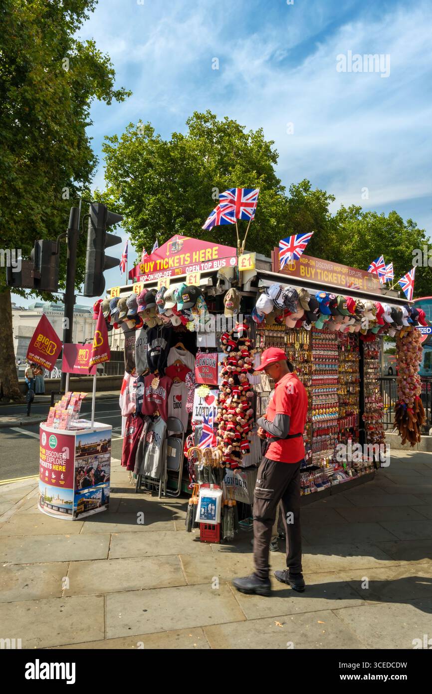 Londres, Angleterre - Un commerçant de Trafalgar Square à côté de son stand de cadeaux touristiques et souvenirs dans le centre de Londres. Banque D'Images