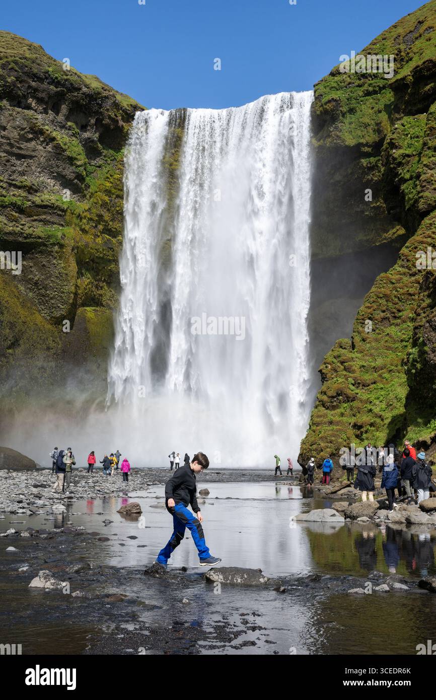 Islande, sud de l'Islande, Vik. Skógafoss, l'une des plus grandes cascades d'Islande, avec une chute de 60 mètres. Touristes devant la cascade. Banque D'Images