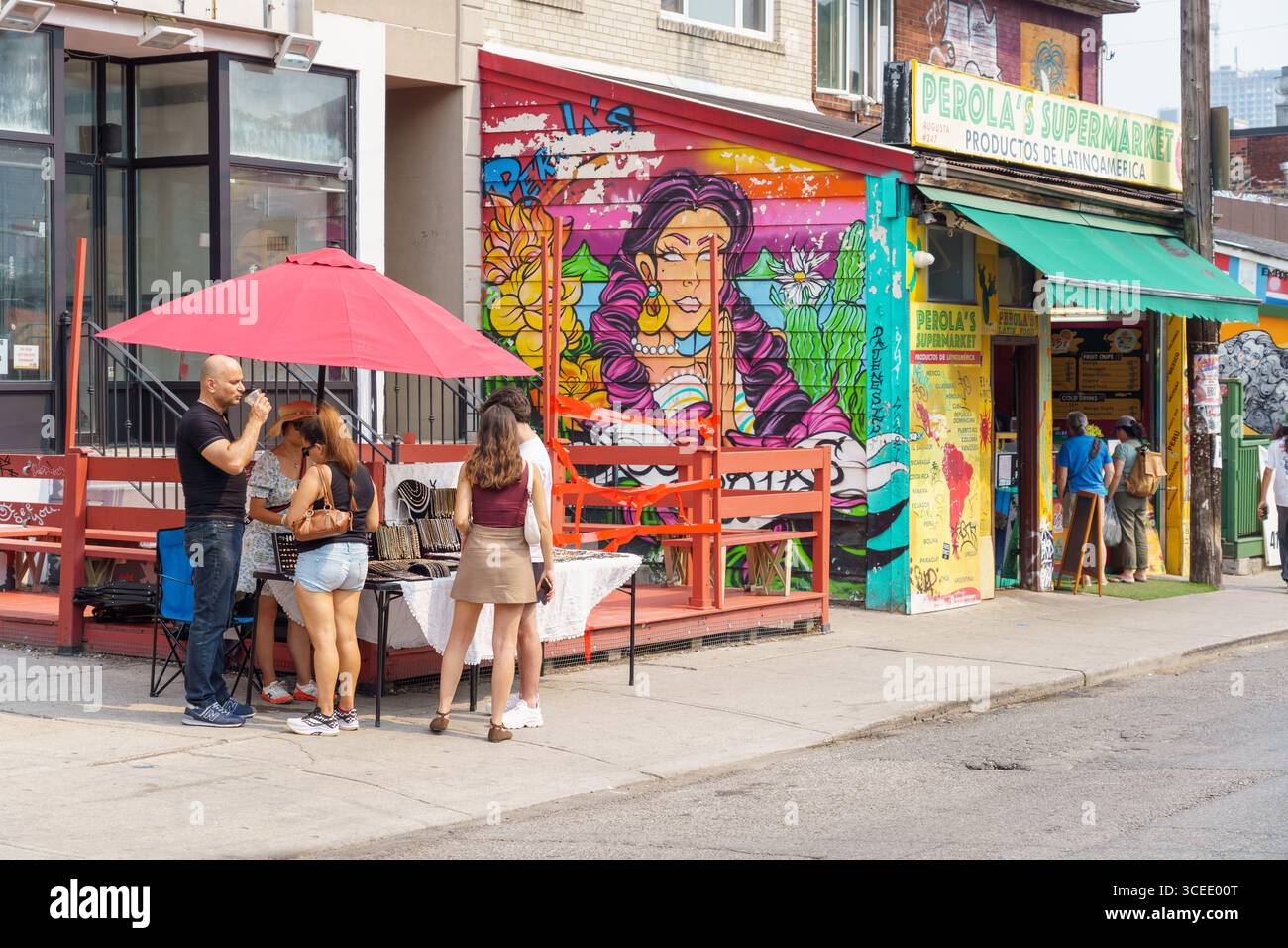 Les gens magasinent dans un stand de bijoux de rue à côté du supermarché Perola avec une peinture murale colorée dans le marché de Kensington. Banque D'Images
