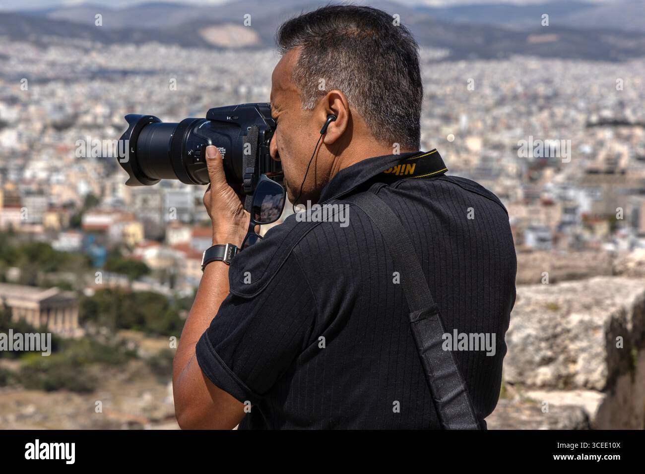 Photographe utilisant un appareil photo Nikon prenant des photos panoramiques de l'Acropole, surplombant Athènes, Grèce Banque D'Images
