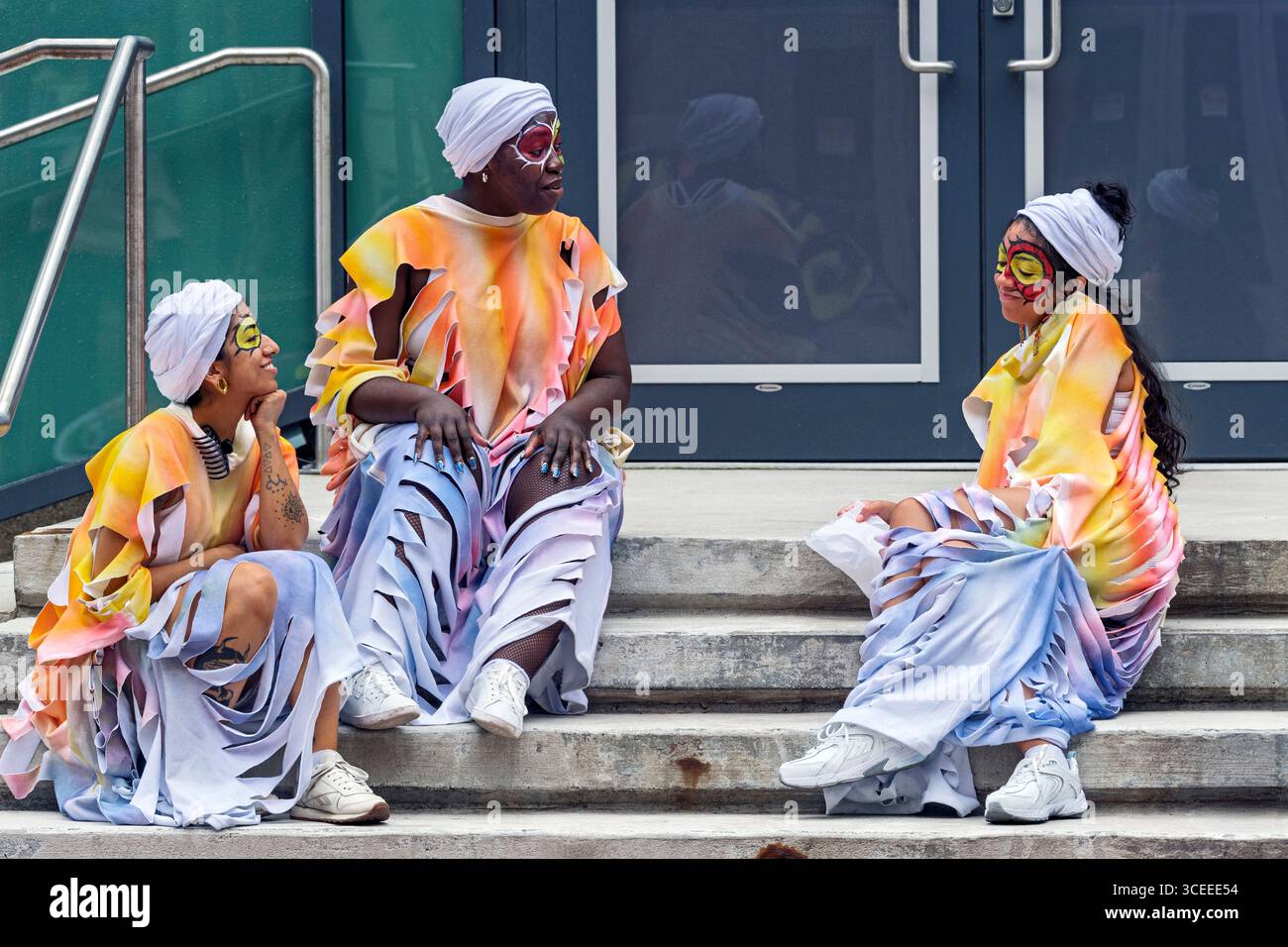 Des femmes avec de la peinture brillante pour le visage et des accessoires accrocheurs alors qu’elles se joignent bientôt au défilé animé Carifest à Calgary, en Alberta. Banque D'Images