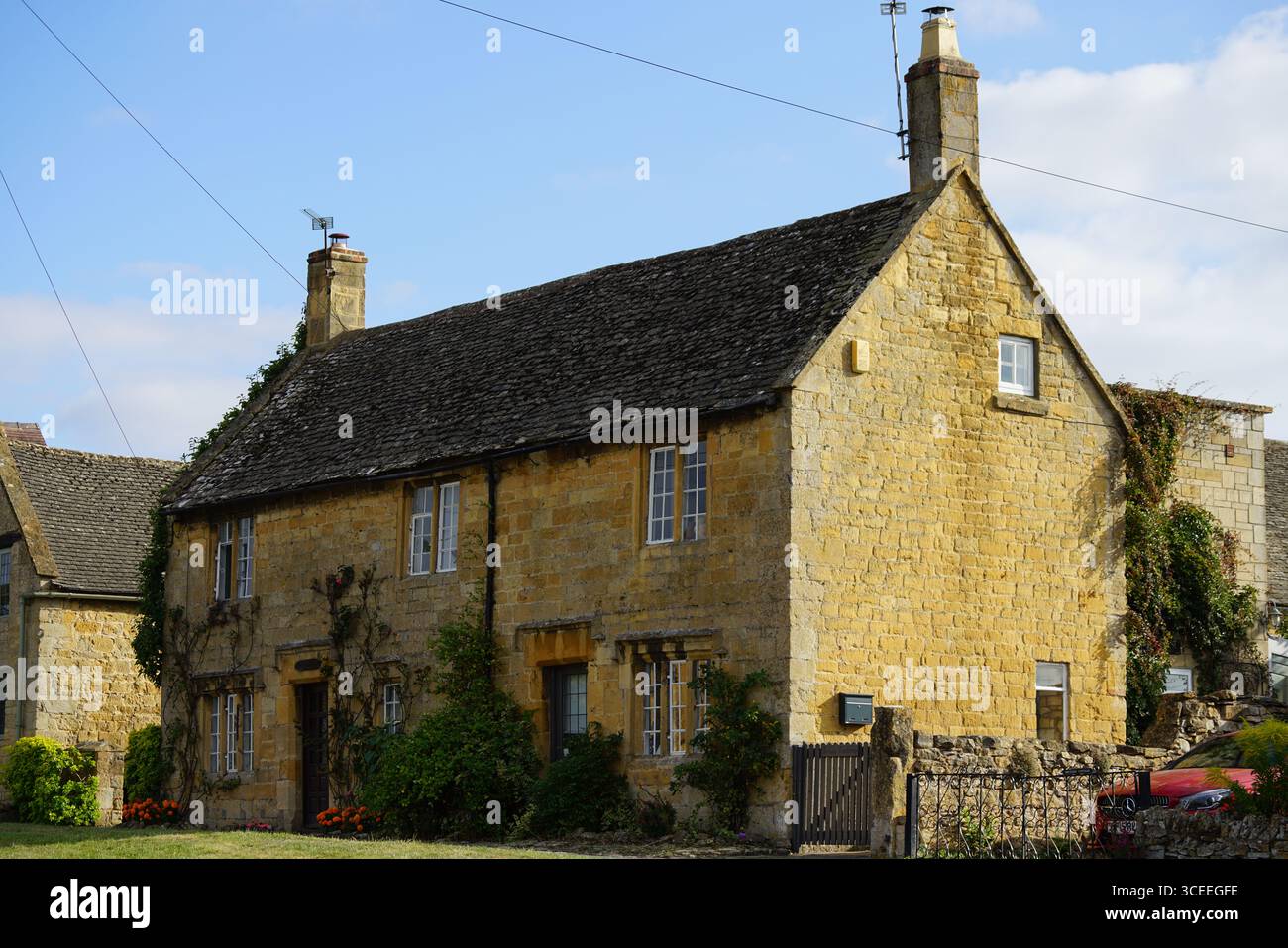 Cottage en pierre traditionnel dans la campagne pittoresque avec ciel bleu et verdure. Willersey, Angleterre Banque D'Images