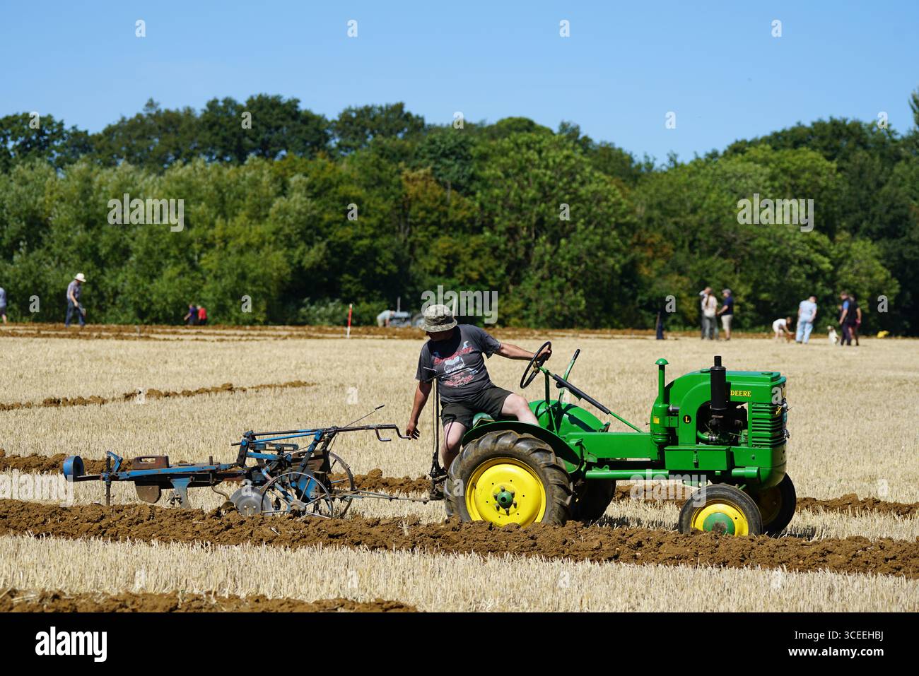 Agriculteur utilisant un tracteur d'époque dans les champs pendant le labourage. Labourage Vintage, Rousham, Angleterre Banque D'Images