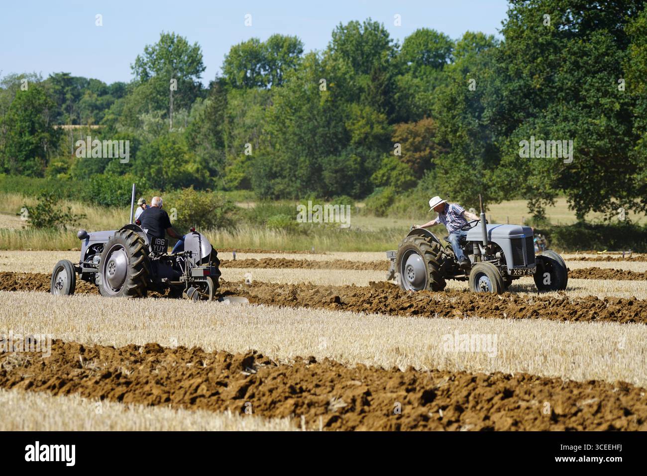Deux agriculteurs utilisant des tracteurs d'époque dans les champs ruraux pendant l'activité agricole. Labourage Vintage, Rousham, Angleterre Banque D'Images