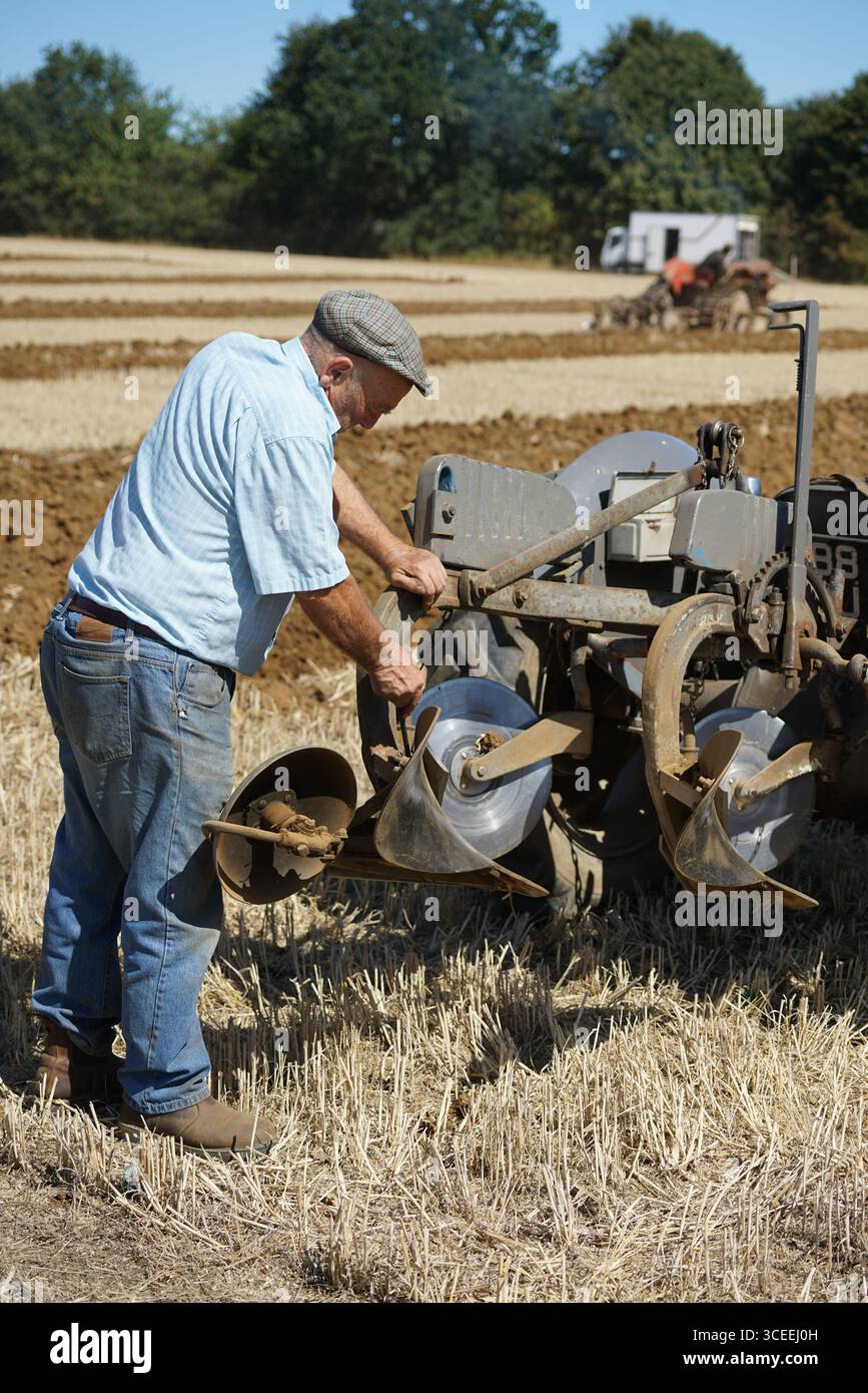 Agriculteur utilisant un tracteur d'époque dans les champs pendant le labourage. Labourage Vintage, Rousham, Angleterre Banque D'Images